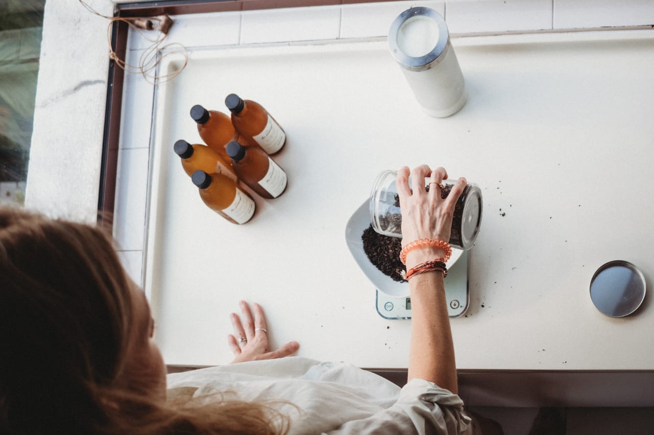 Founder brewing kombucha at a sunlit kitchen counter